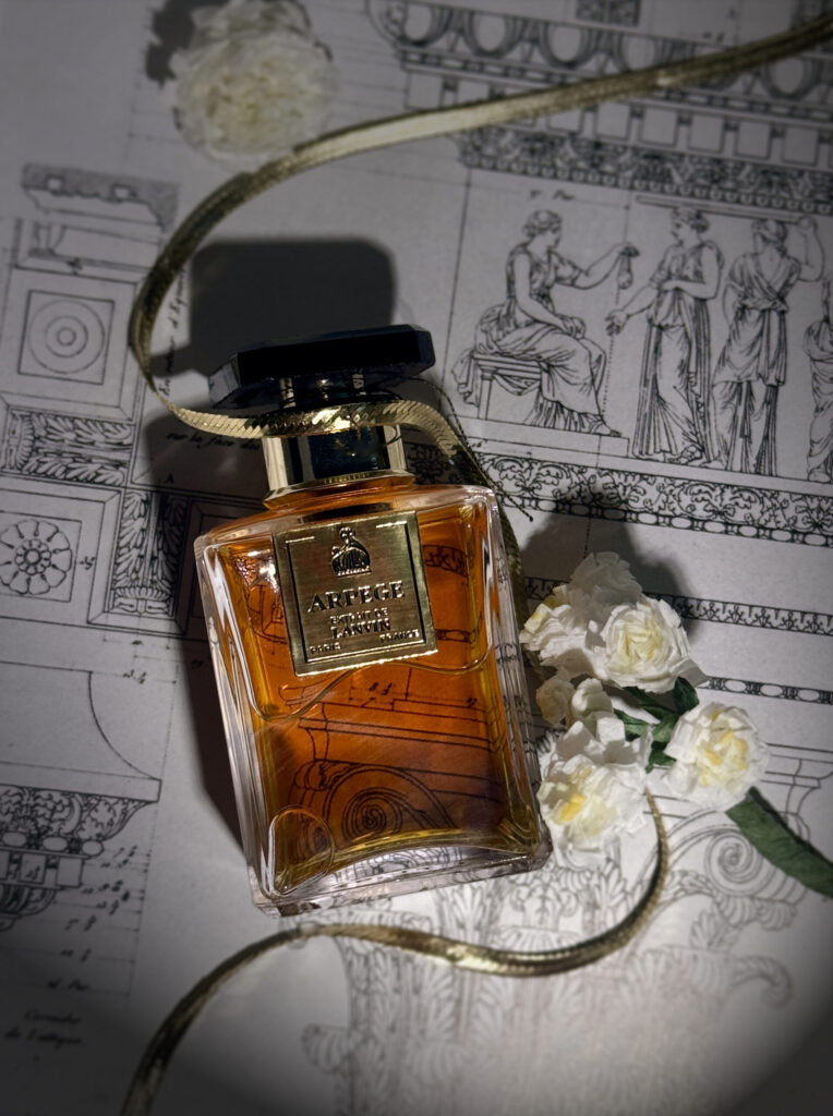 A bottle of Arpege Extrait wrapped in a gold chain with white flowers next to it on top of an open book with diagrams of greek architecture.